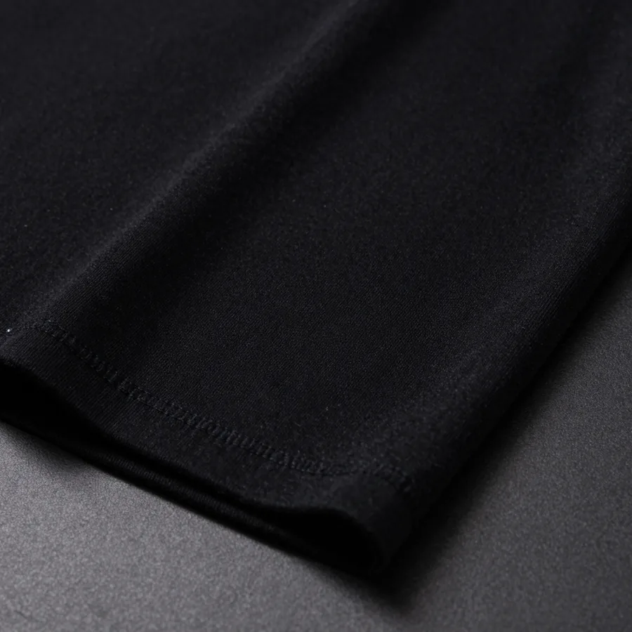 Close macro detail of the material and construction of a black heavyweight cotton t-shirt with a tonal black-on-black P monogram surface.