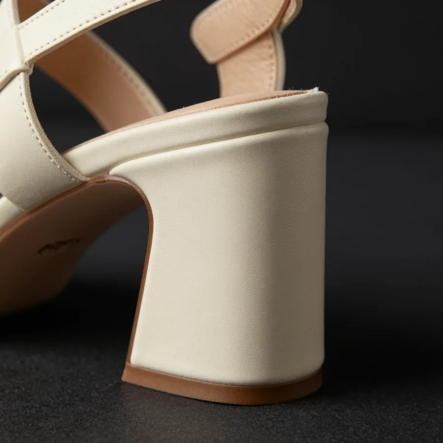 Close macro detail of the material and construction of a bone ivory leather sandal on a sculptural angular block heel.