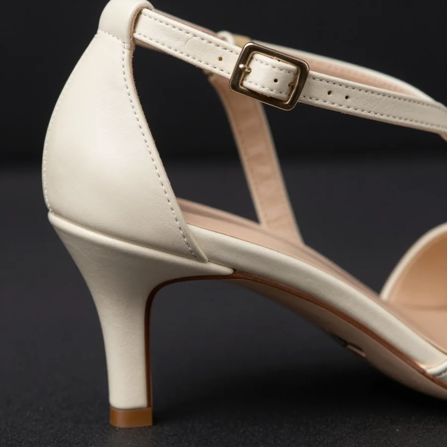 Close macro detail of the material and construction of a bone ivory leather strappy heel with a discreet P at the ankle fastening.