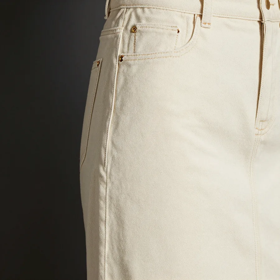 Close macro detail of the seam construction of a floor-length bone washed denim column skirt with the trademark house seam opening the front panel.