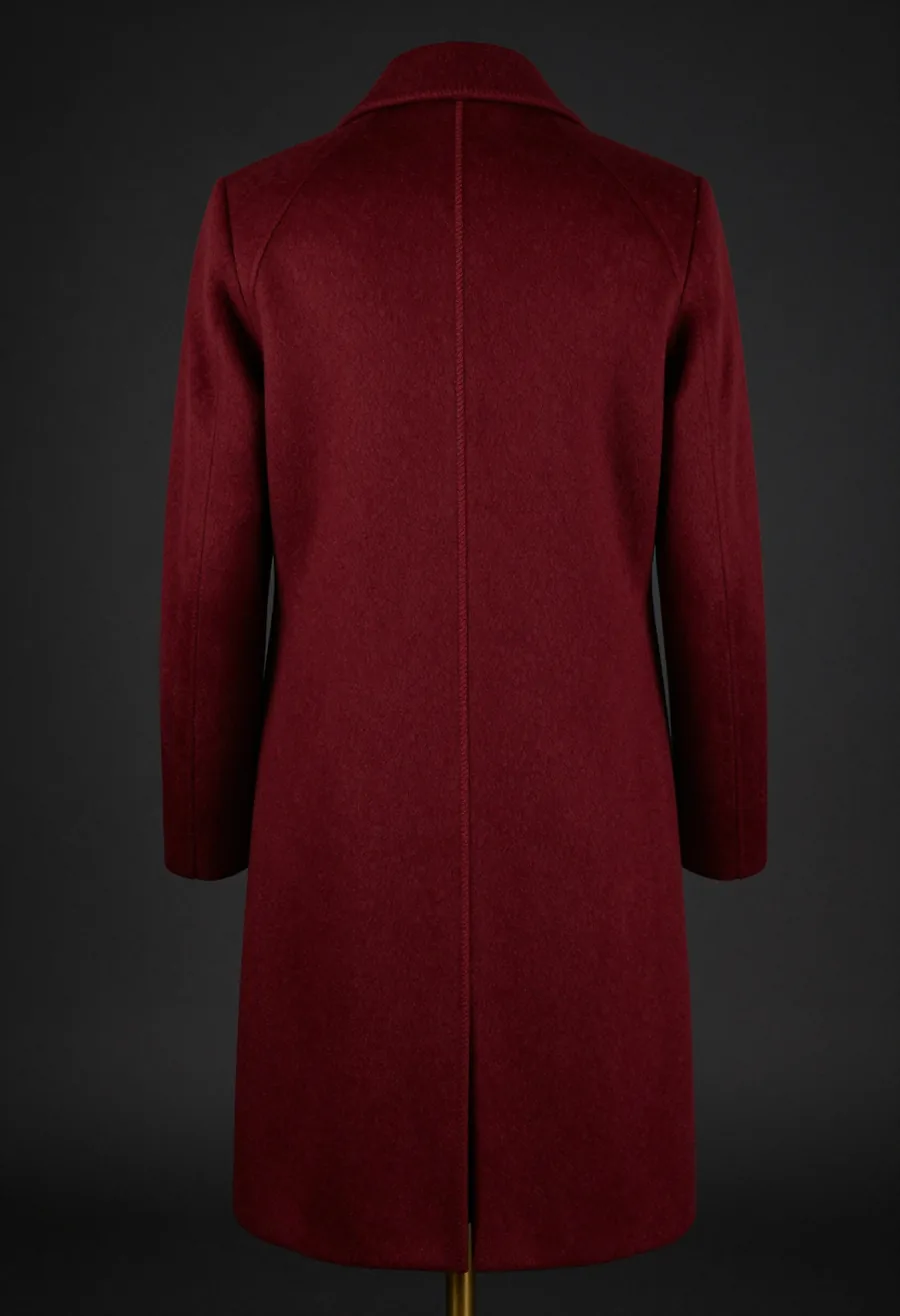 Studio product shot, back view, of a floor-brushing oxblood wool overcoat with the trademark house seam running the full front panel, on a dark ground.