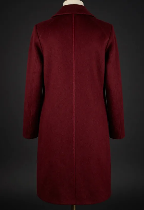 Studio product shot, front view, of a floor-brushing oxblood wool overcoat with the trademark house seam running the full front panel, on a dark ground.